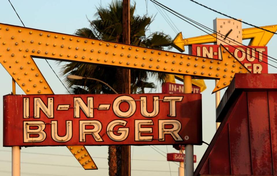 In-N-Out Burger signs, two in the foreground from the fast food chain's original location and one in the background at a new location in Baldwin Park, California.